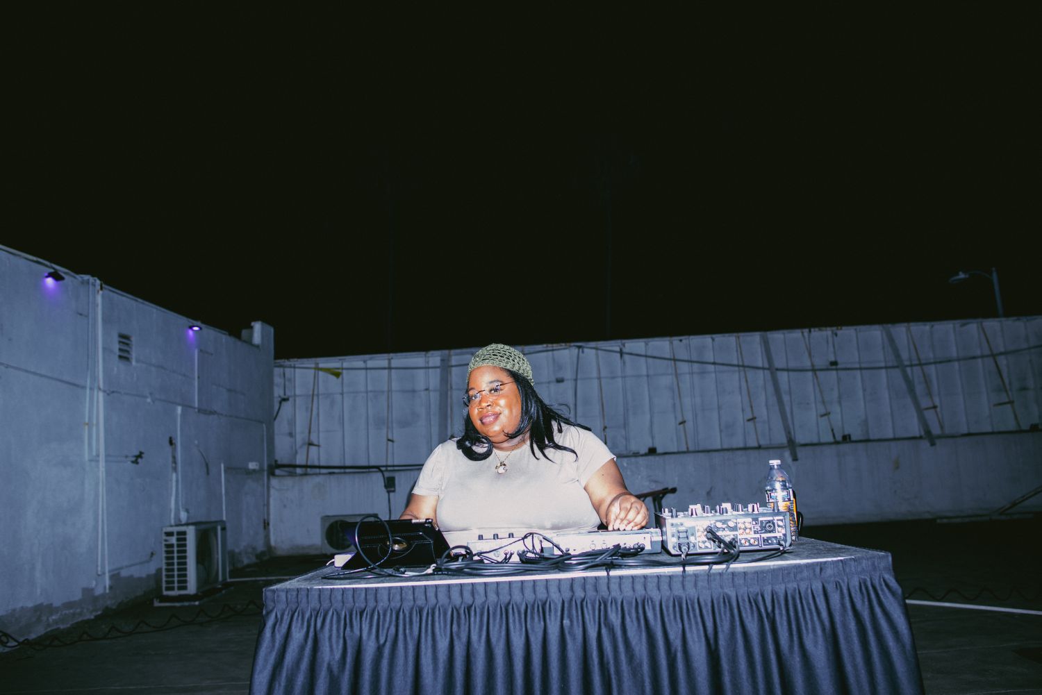 Female DJ performing a live set on a rooftop at night during the American Autoflower Cup cannabis event in Los Angeles